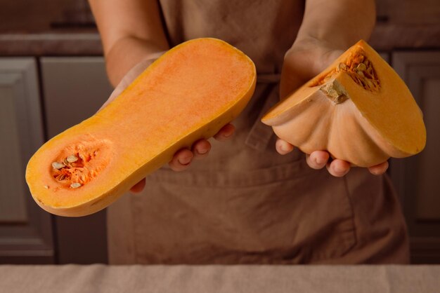 Photo pumpkin cut in half in woman chef hands in kitchen ready for cook easy and healthy dish at home