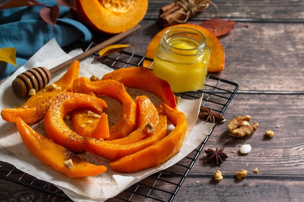 Pumpkin dessert Baked pumpkin slices with honey cinnamon and walnuts on a rustic table Copy space