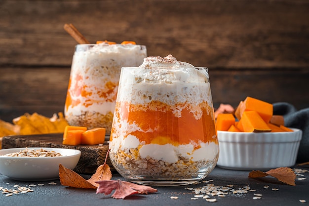 Pumpkin dessert with cream and cereals on a wooden background. Side view, close-up.
