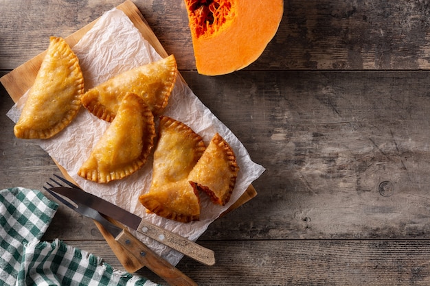 Pumpkin empanadillas on wooden table.