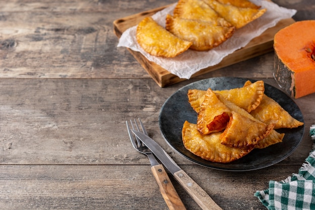 Pumpkin empanadillas on wooden table.