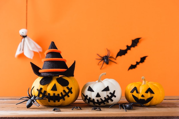 pumpkin ghost scary jack o lantern face, black spider and bats on wooden table