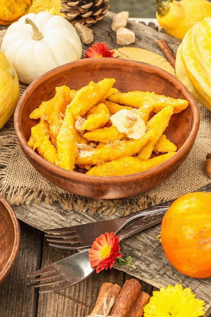 Pumpkin gnocchi or Italian dumplings. Healthy vegetarian squash dish with cottage cheese. Autumn decor with fall leaves, cones, ripe whole pumpkins, flowers and spices. Old wooden background, close up