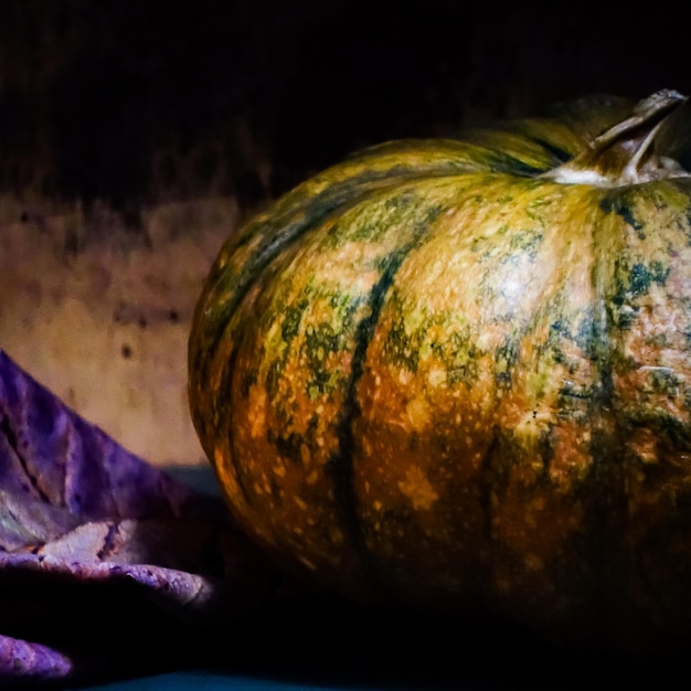 Foto zucca di colore verde e giallo sul tavolo isolato su sfondo scuro concetto di halloween