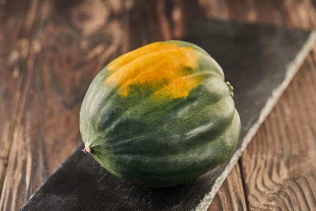 Pumpkin greenyellow on black stone on wooden background