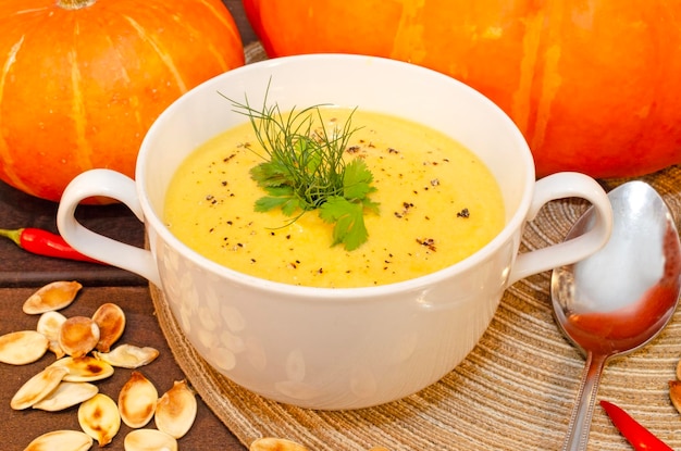 Pumpkin hot puree soup on a wooden table