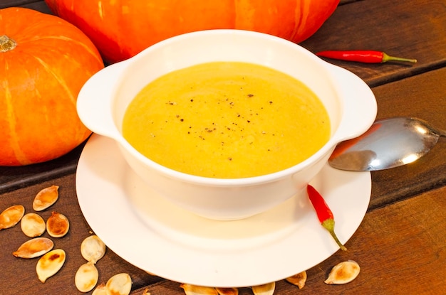 Pumpkin hot puree soup on a wooden table