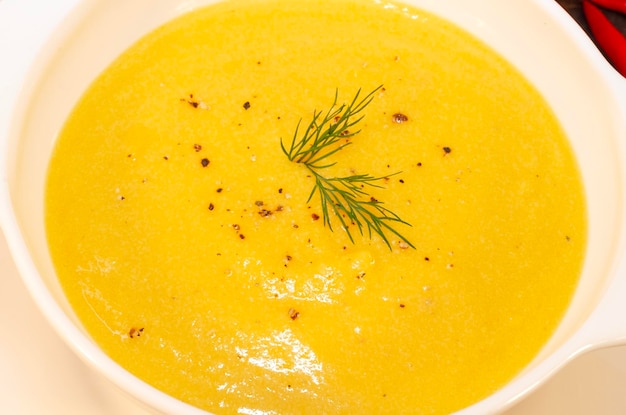 Pumpkin hot soup puree and pumpkins on a wooden table