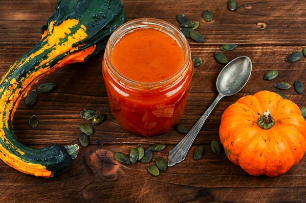 Photo pumpkin jam in a glass jar and fresh pumpkins pumpkin marmalade close up