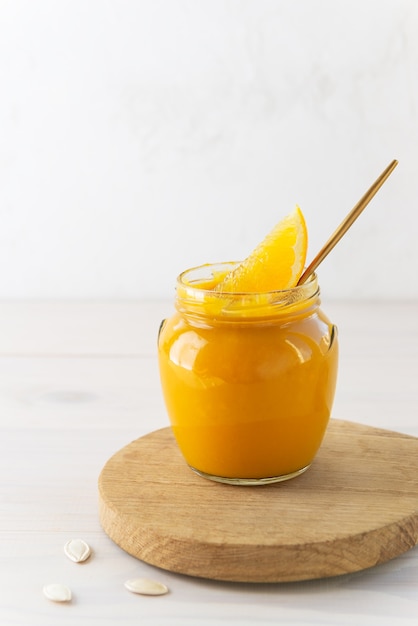 Pumpkin jam with orange in a glass jar on a board