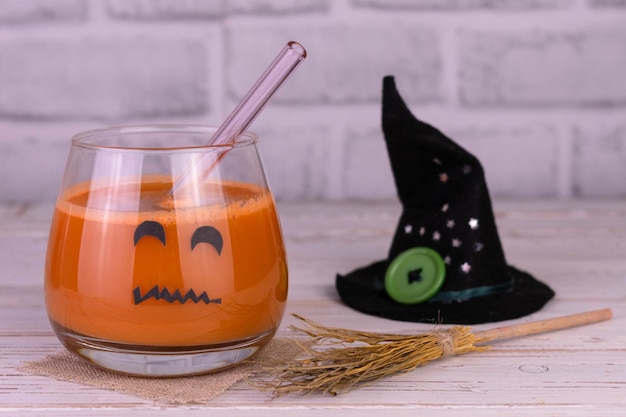 Pumpkin juice in a glass with a scary muzzle and a witch hat.Drinks for Halloween party