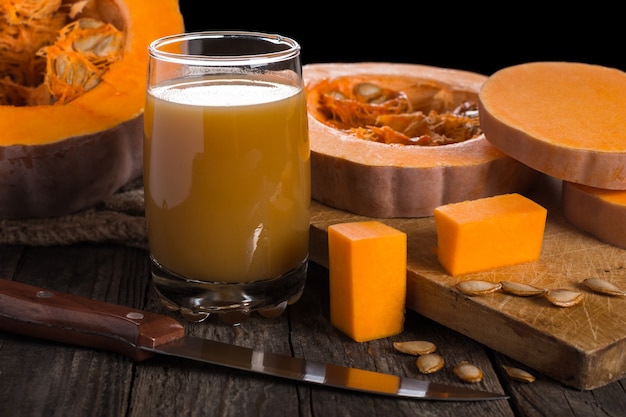 Pumpkin juice in grass on wooden table