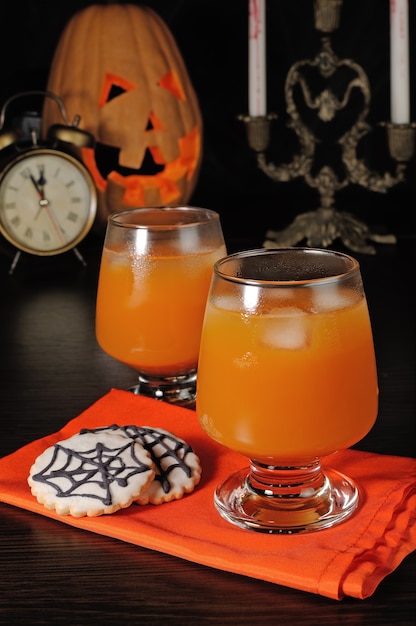 Pumpkin juice with ice on a napkin with cookies for Halloween