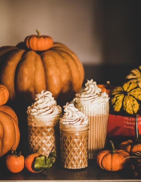 Pumpkin latte coffee with whipped cream in glasses on table