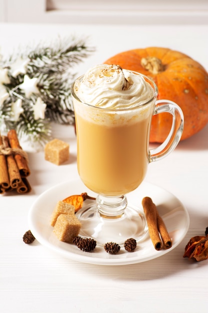 Pumpkin latte with spices on a white wooden table