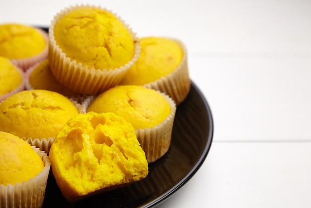 Pumpkin muffins on black plate on white wooden table Halved cupcake closeup selective focus