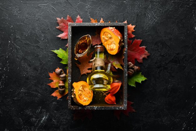 Pumpkin oil and pumpkins Autumn vegetables flat lay On a black stone background Top view Free space for your text