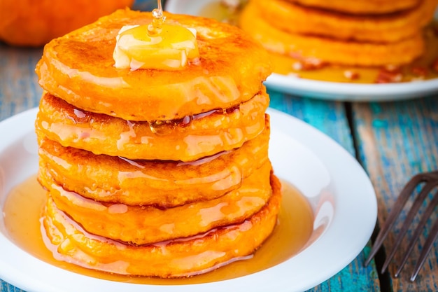 Pumpkin pancakes with honey and butter on wooden table