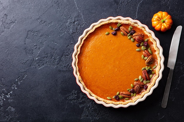 Pumpkin pie in baking dish Black slate background Copy space Top view