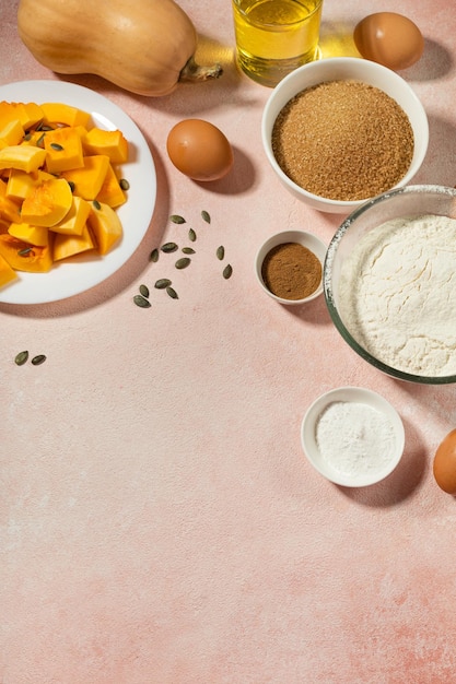 Pumpkin pie ingredients in bowls on pink table