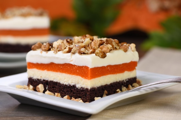 Pumpkin pie light creamy dessert with cheese cream and pumpkin layers topped with chopped nuts