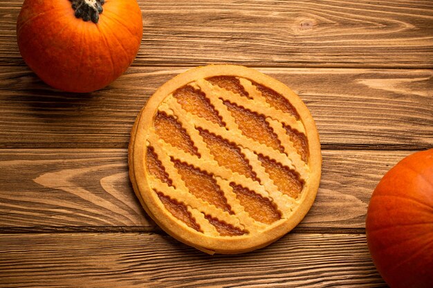 Pumpkin pie on rustic wooden background with whole pumpkins. Traditional American autumn, Thanksgiving and Halloween sweet pie, seasonal fall dessert. Close up, top view