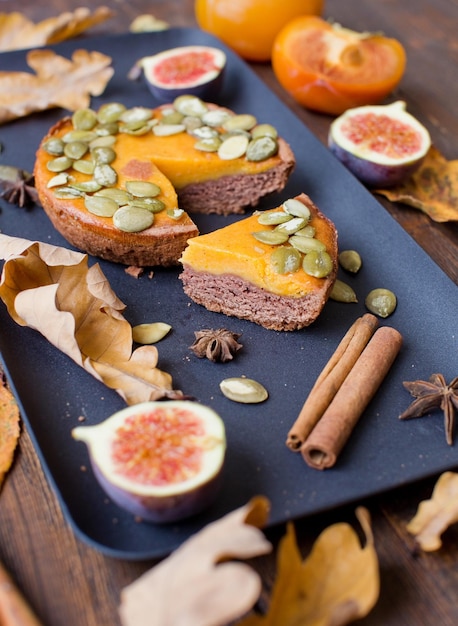 Pumpkin pie slice on black plate with figs cinnamon sticks star anise and persimmons Autumn thanksgiving dinner concept Tasty autumn bakery