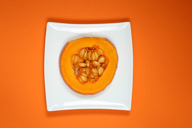 Pumpkin piece on a white plate on an orange surface