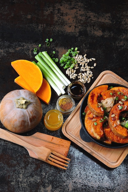 Pumpkin pieces baked in a small frying pan with greens and seeds. Baked pumpkin. Vegan lunch with spicy baked pumpkin. Useful autumn snack. Halloween lunch.