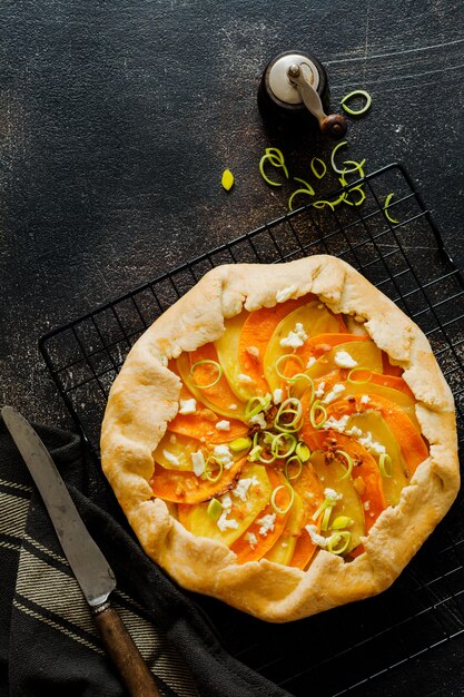 Piatto di torta galette di zucca, patate, formaggio feta e porri sulla superficie del tavolo in cemento grigio. vista dall'alto.