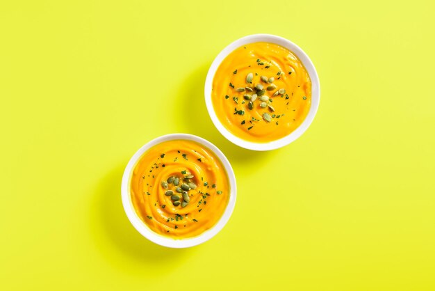 Pumpkin puree in bowls over yellow background with free text space Healthy diet food concept