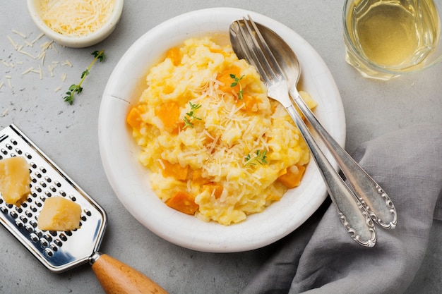 Pumpkin risotto with thyme, garlic, parmesan cheese and white wine on gray concrete surface