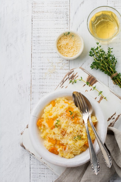 Pumpkin risotto with thyme, garlic, parmesan cheese and white wine on light wooden surface