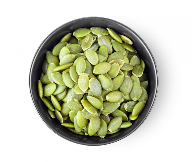 Pumpkin seeds in a bowl on a white table. 