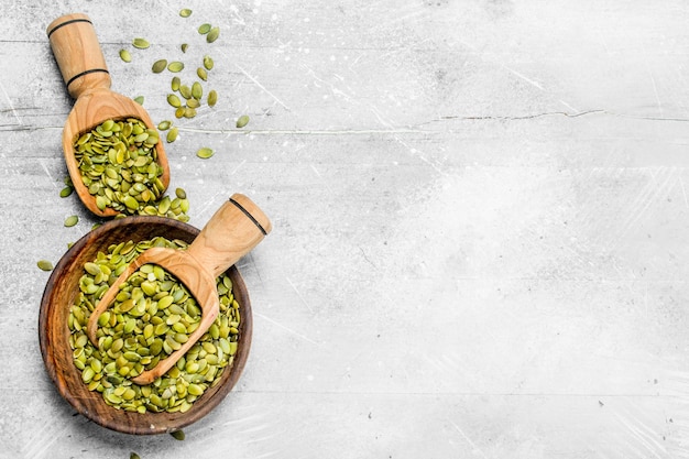 Pumpkin seeds in bowl with wooden scoop