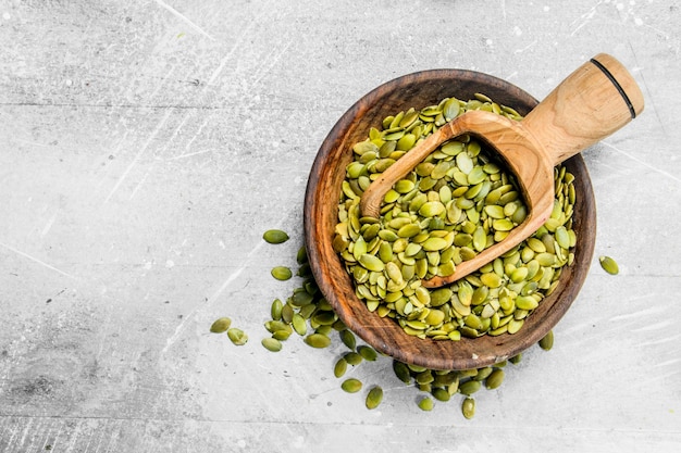 Pumpkin seeds in bowl with wooden scoop