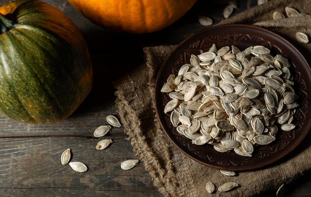 Pumpkin seeds on a brown plate on a wooden background