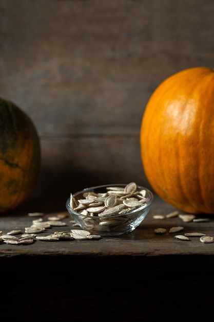 Pumpkin seeds in a glass saucer on a wooden background