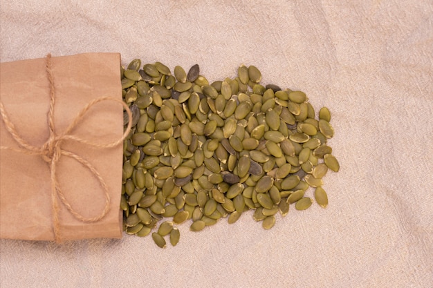 Pumpkin seeds in a paper bag on natural linen. pumpkin seeds vitamins of group b