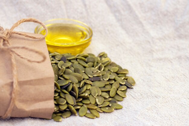 Pumpkin seeds in a paper bag, pumpkin seed oil on natural linen. pumpkin seeds vitamins of group B and magnesium.