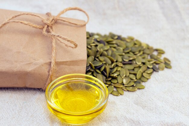 Pumpkin seeds in a paper bag, pumpkin seed oil on natural linen. pumpkin seeds vitamins of group b and magnesium.