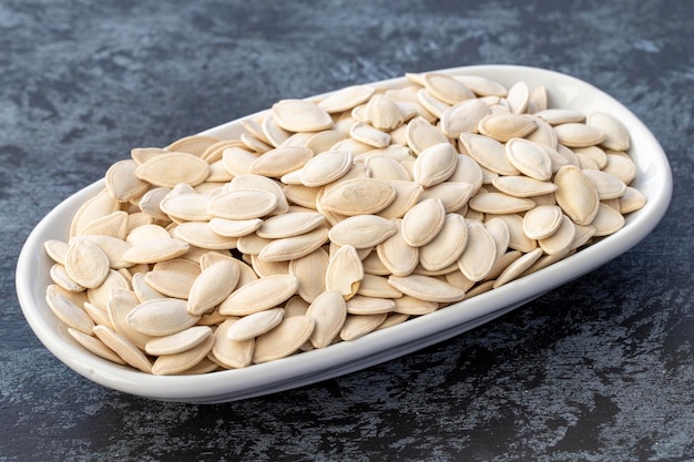 Pumpkin seeds on plate on dark background