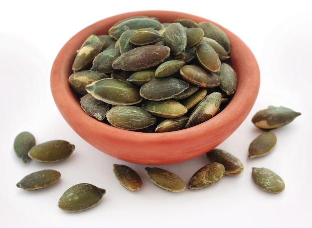 Pumpkin seeds roasted in a bowl over white background