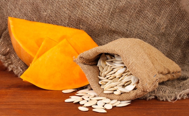 Pumpkin seeds in sack on wooden background