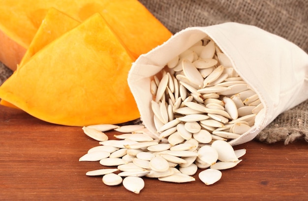 Pumpkin seeds in sack on wooden background