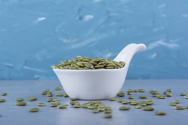 Pumpkin seeds in a spoon, on the marble.