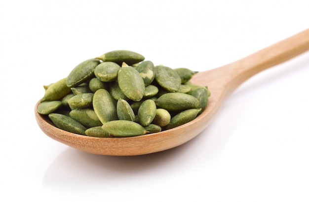 Pumpkin seeds in the spoon on white space