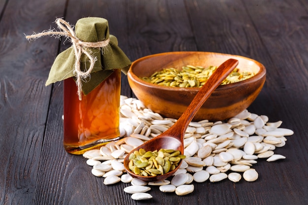 Pumpkin seeds and on the table, virgin pumpkin oil in a glass jar