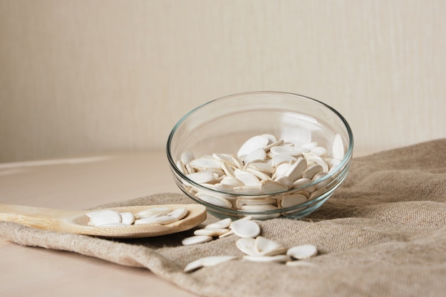 Pumpkin seeds in white bowl and spoon on the flax on the table