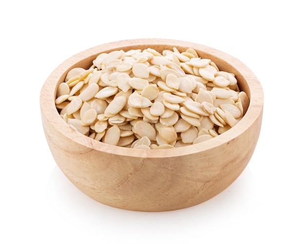 Pumpkin seeds in wood bowl on white table. 